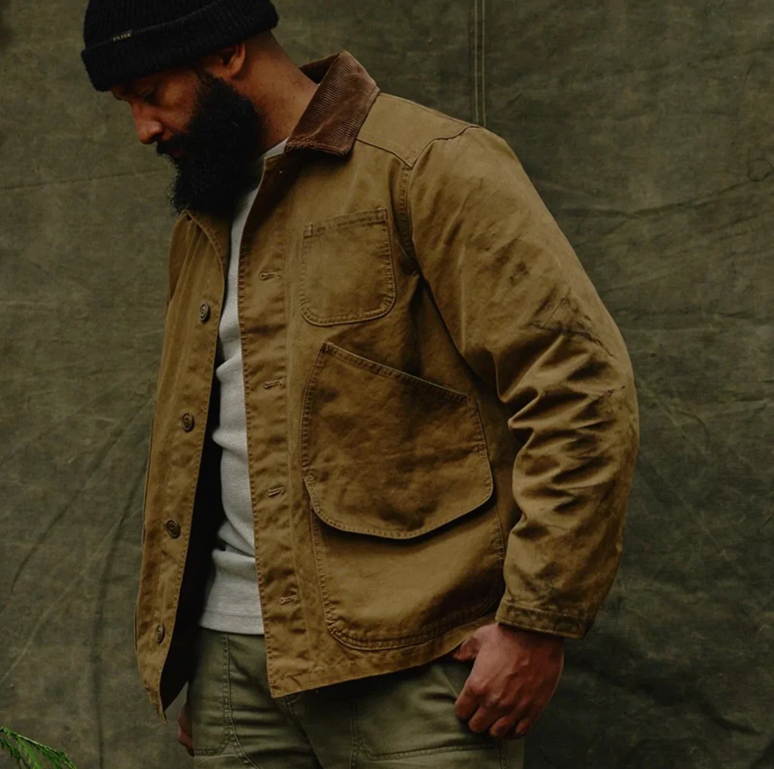 a man wearing Filson Canvas Outfitter Barn Men's Jacket Coat for  outdoor wear. 