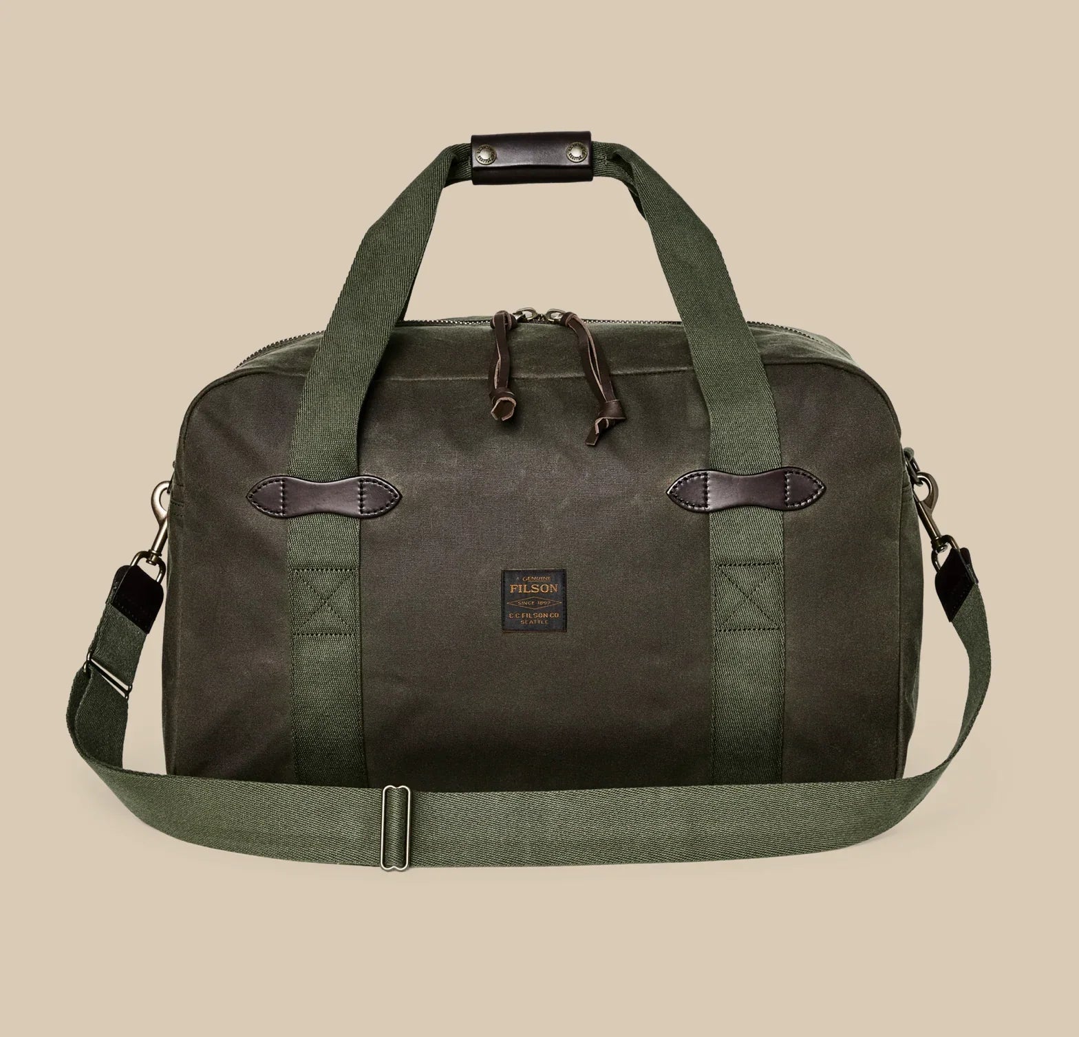 Filson TIn Cloth Medium Duffle in dark brown with zippered compartments, leather accents, and convertible duffle‑to‑backpack straps.