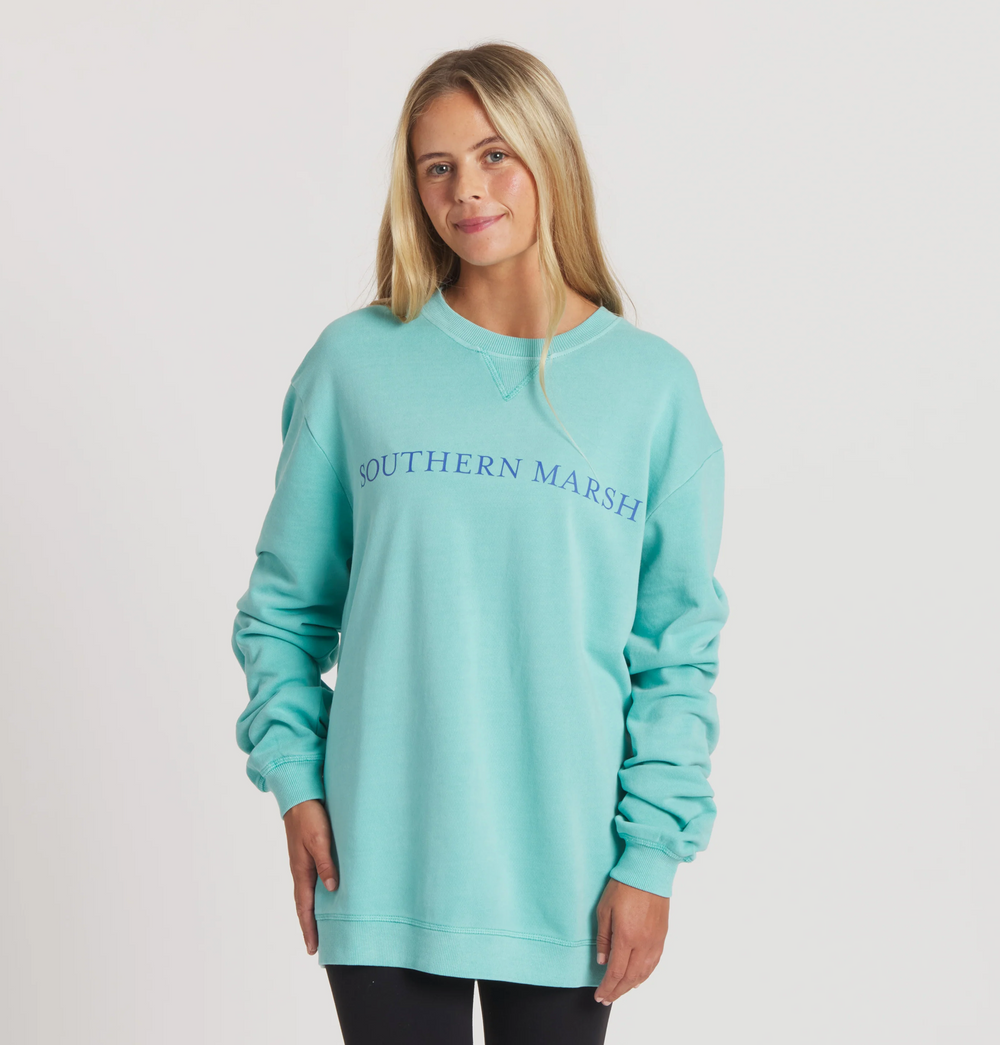 Woman wearing a light blue sweatshirt with 'Southern Marsh' logo for women's casual, everyday wear.