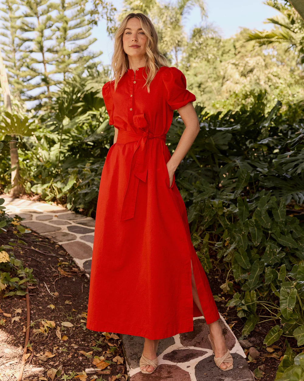 A woman wearing Southern Tide Mary Ann Maxi Dress in poppy red with short sleeves, button‑down front, and waist belt, soft cotton blend fabric standing outdoor for office or date night