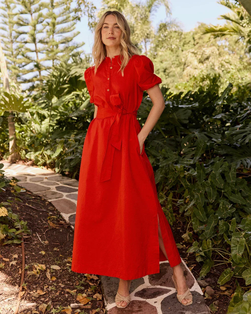 A woman wearing Southern Tide Mary Ann Maxi Dress in poppy red with short sleeves, button‑down front, and waist belt, soft cotton blend fabric standing outdoor for office or date night