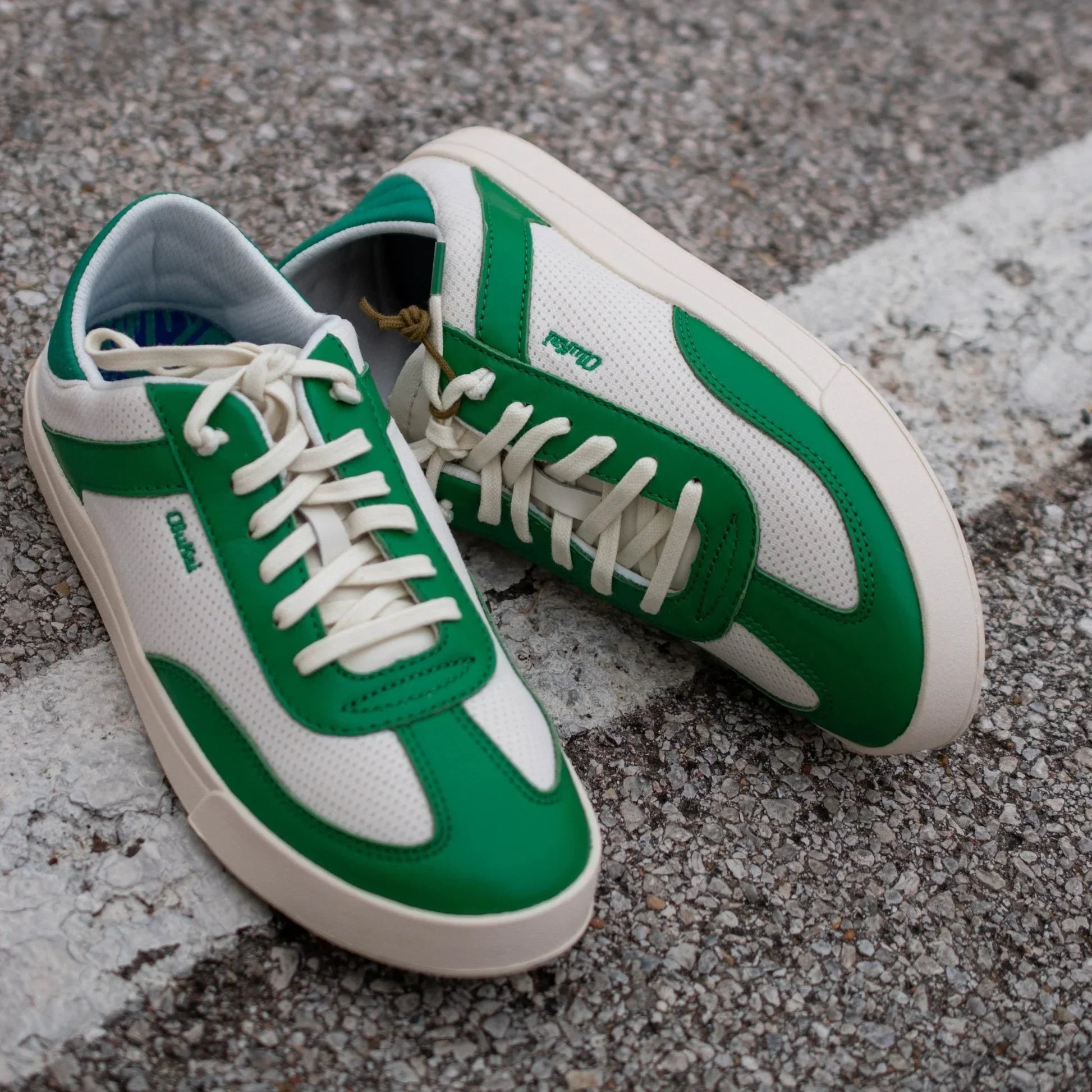 Olukai Women’s Kīlea Green sneaker shoe in off-white and bamboo, featuring lace-up design, breathable mesh, suede overlays, and cushioned sole for everyday comfort.